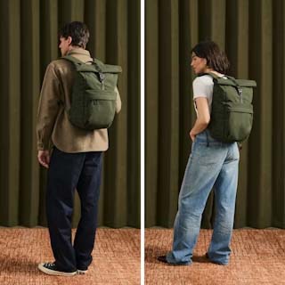 在绿色窗帘和深色地毯前,两位模特背着橄榄绿色的 Velroy Classic 卷顶背包,强调舒适和时尚。 在绿色窗帘和深色地毯前,两位模特背着橄榄绿色的 Velroy Classic 卷顶背包,强调舒适和时尚。